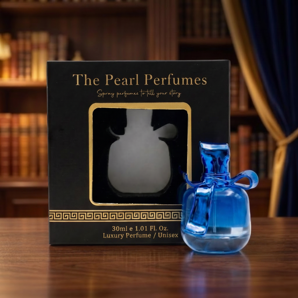 A small cobalt blue glass perfume bottle with a loop handle stands beside its black retail box with gold lettering, placed on a wooden table with a blurred library background.